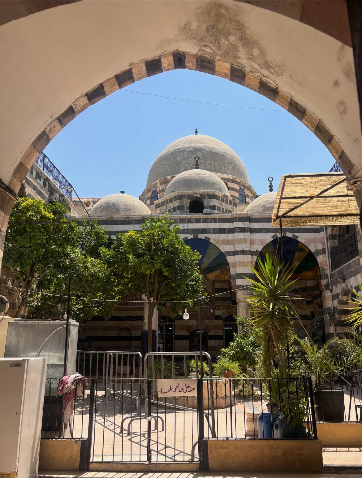 Domes of a mosque with striped stonework framed by an arch