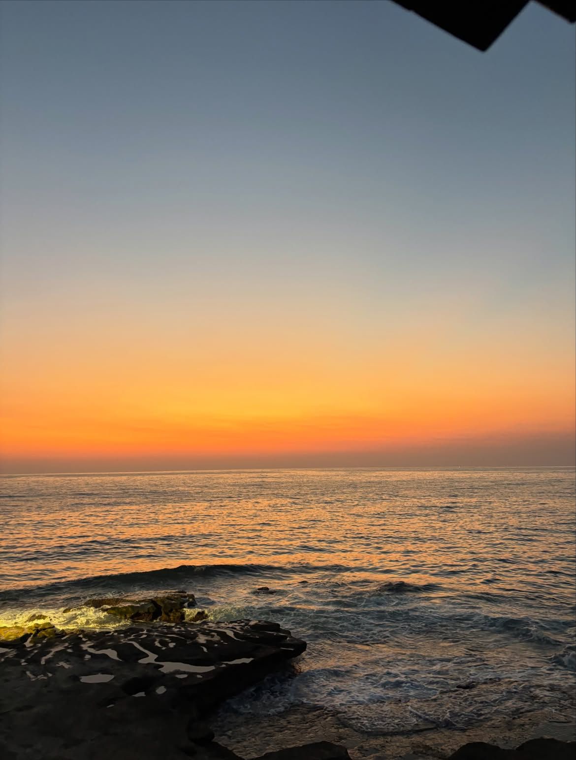 Orange sunset over the sea with dark rocks