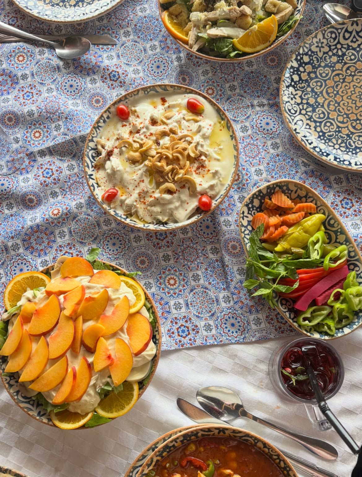A table of mezze in patterned bowls on a tiled cloth